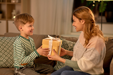 Image showing little son giving present to mother at home