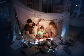 Image showing Family sitting in a teepee, having fun with the flashlight