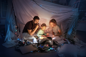 Image showing Family sitting in a teepee, reading stories with the flashlight