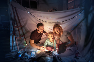 Image showing Family sitting in a teepee, having fun with the flashlight