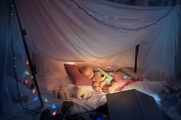 Image showing Little girl lying in a teepee, sleeping with the flashlight