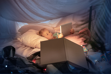 Image showing Little girl lying in a teepee, playing with the flashlight