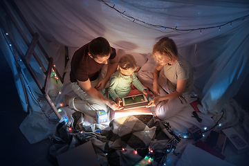 Image showing Family sitting in a teepee, reading stories with the flashlight