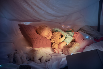 Image showing Little girl lying in a teepee, sleeping with the flashlight