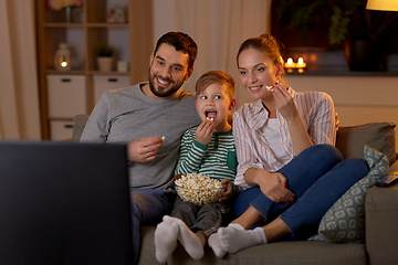 Image showing happy family with popcorn watching tv at home