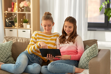 Image showing happy girls with tablet pc sitting on sofa at home