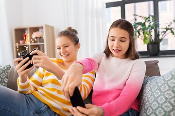 Image showing girls and playing game on smartphones at home