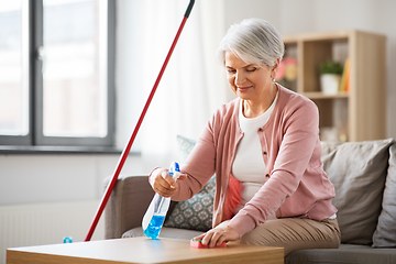 Image showing senior woman with detergent cleaning table at home