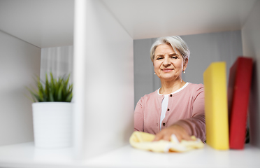 Image showing happy senior woman with cloth dusting rack at home