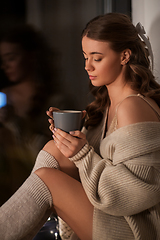 Image showing woman with coffee or tea cup at window at home