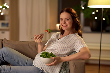 Image showing happy smiling pregnant woman eating salad at home