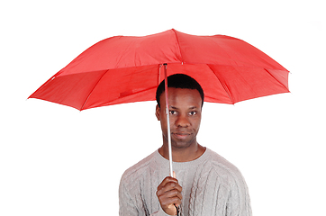 Image showing Black man standing and holding a red umbrella