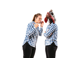 Image showing Young handsome woman arguing with herself as a chicken on white studio background.