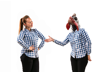 Image showing Young handsome woman arguing with herself as a chicken on white studio background.