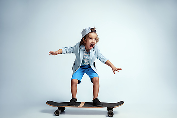 Image showing Pretty young boy on skateboard in casual clothes on white studio background