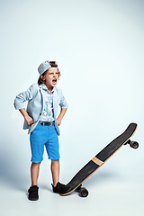 Image showing Pretty young boy on skateboard in casual clothes on white studio background