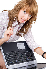 Image showing The young woman in glasses sits with the laptop. Isolated on whi