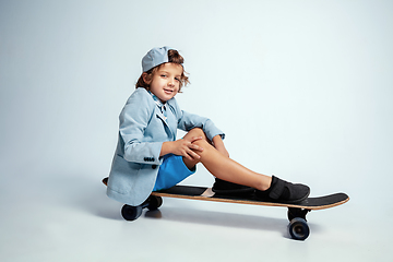 Image showing Pretty young boy on skateboard in casual clothes on white studio background