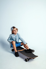 Image showing Pretty young boy on skateboard in casual clothes on white studio background