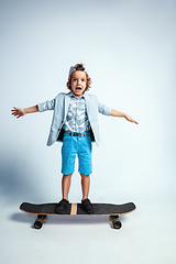 Image showing Pretty young boy on skateboard in casual clothes on white studio background