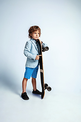 Image showing Pretty young boy on skateboard in casual clothes on white studio background