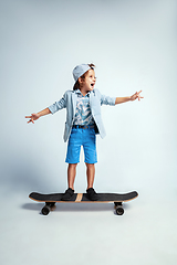 Image showing Pretty young boy on skateboard in casual clothes on white studio background