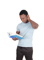 Image showing Puzzled African man looking at his book