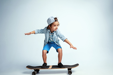 Image showing Pretty young boy on skateboard in casual clothes on white studio background