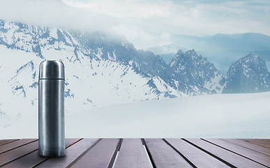 Image showing Thermos with tea or coffee and landscape of mountains on background