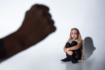 Image showing Sad and frightened little girl with bloodshot and bruised eyes sitting scared