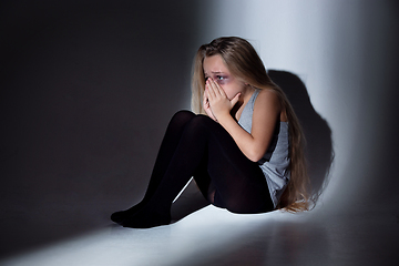 Image showing Sad and frightened little girl with bloodshot and bruised eyes sitting scared