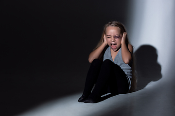 Image showing Sad and frightened little girl with bloodshot and bruised eyes sitting scared