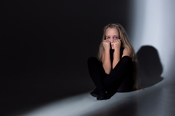 Image showing Sad and frightened little girl with bloodshot and bruised eyes sitting scared