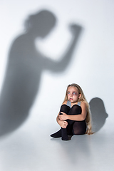 Image showing Sad and frightened little girl with bloodshot and bruised eyes sitting scared