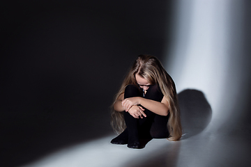 Image showing Sad and frightened little girl with bloodshot and bruised eyes sitting scared