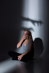 Image showing Sad and frightened little girl with bloodshot and bruised eyes sitting scared