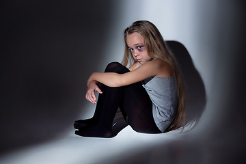 Image showing Sad and frightened little girl with bloodshot and bruised eyes sitting scared