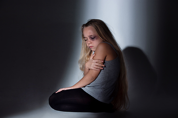 Image showing Sad and frightened little girl with bloodshot and bruised eyes sitting scared