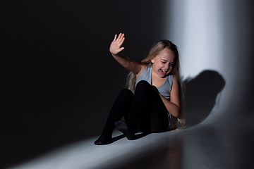 Image showing Sad and frightened little girl with bloodshot and bruised eyes sitting scared