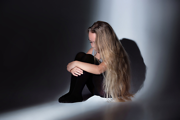 Image showing Sad and frightened little girl with bloodshot and bruised eyes sitting scared