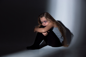 Image showing Sad and frightened little girl with bloodshot and bruised eyes sitting scared