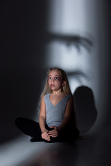 Image showing Sad and frightened little girl with bloodshot and bruised eyes sitting scared