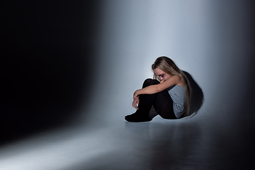 Image showing Sad and frightened little girl with bloodshot and bruised eyes sitting scared