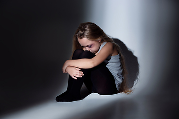 Image showing Sad and frightened little girl with bloodshot and bruised eyes sitting scared