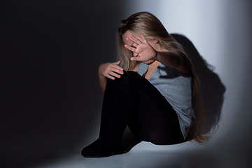 Image showing Sad and frightened little girl with bloodshot and bruised eyes sitting scared