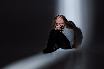 Image showing Sad and frightened little girl with bloodshot and bruised eyes sitting scared