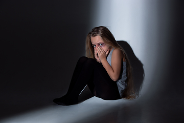 Image showing Sad and frightened little girl with bloodshot and bruised eyes sitting scared