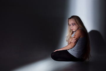 Image showing Sad and frightened little girl with bloodshot and bruised eyes sitting scared