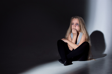 Image showing Sad and frightened little girl with bloodshot and bruised eyes sitting scared