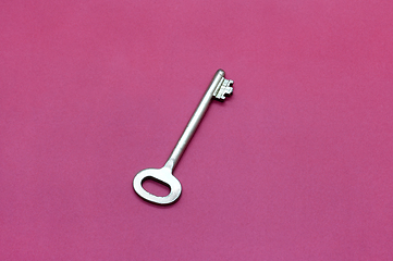 Image showing Metal key on bright crimson paper 
